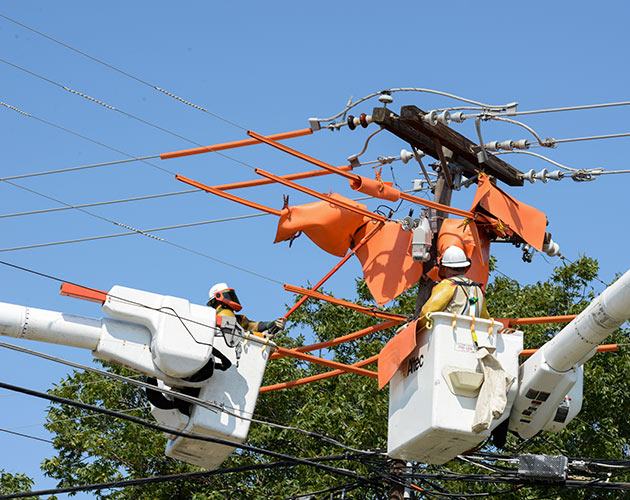 two linemen in bucket of a truck grounding cables for a tripsaver fuse with trees in the background and clear blue sky lateral protection, install lateral protection, tripsaver, tripsaver 2, installing tripsaver